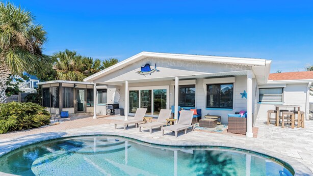 A modern house with a swimming pool, covered patio with lounge chairs, and a decorative star on the roof.