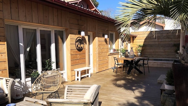 Een houten terras met tuinmeubilair, waaronder een tafel, stoelen en een bank.
