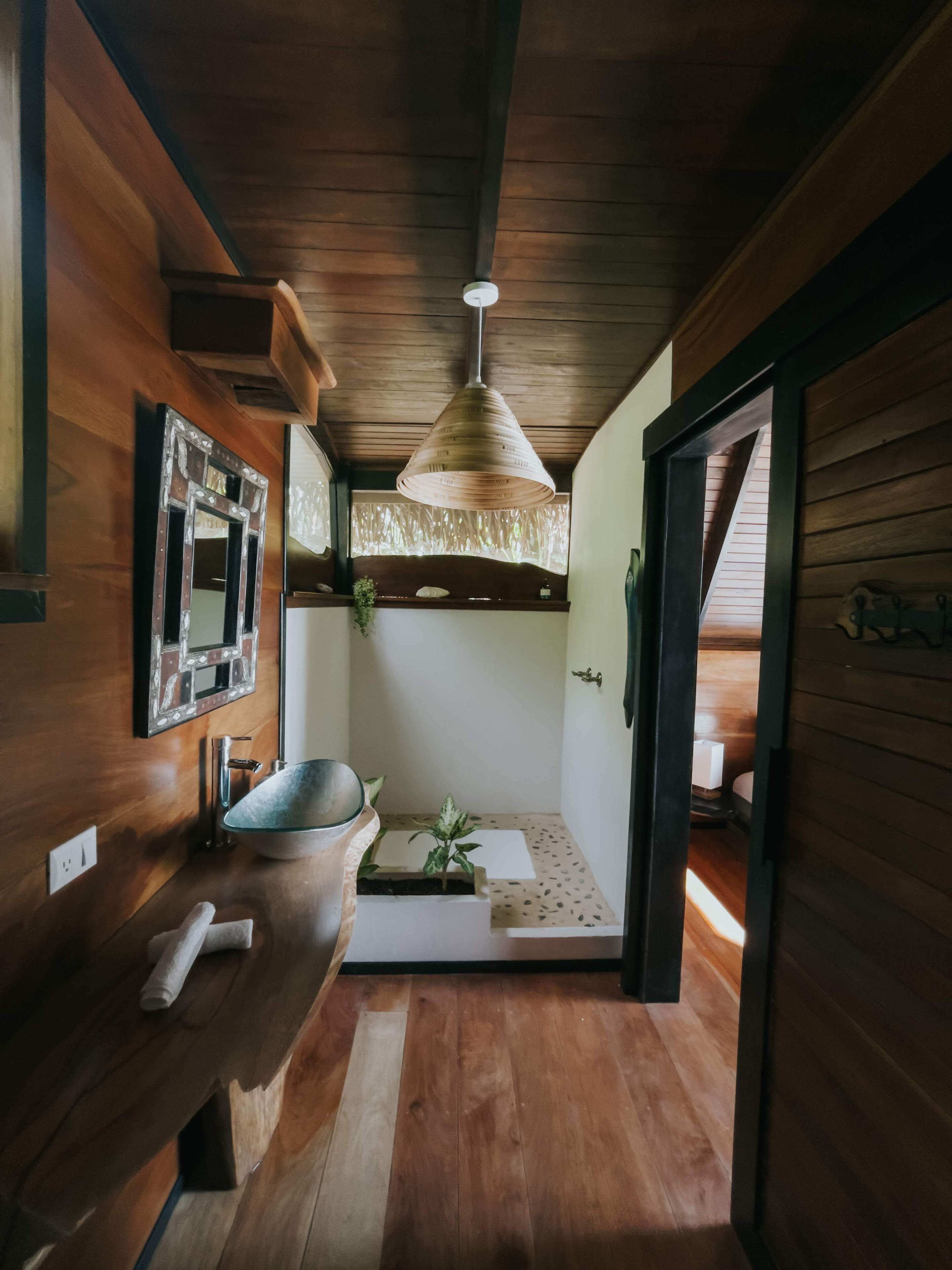 A wooden interior with a sink, mirror, and pendant light.