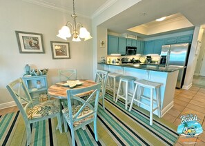 A kitchen with blue cabinets, a central island with stools, and a striped rug.