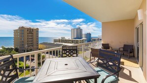 A balcony with a table and chairs, overlooking a beach and buildings. - Lazy River and Indoor Pool Sleeps 8 CT605 (Gulf Shores)