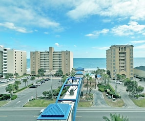 Un hotel costero con varios edificios altos, un estacionamiento y vista al océano.