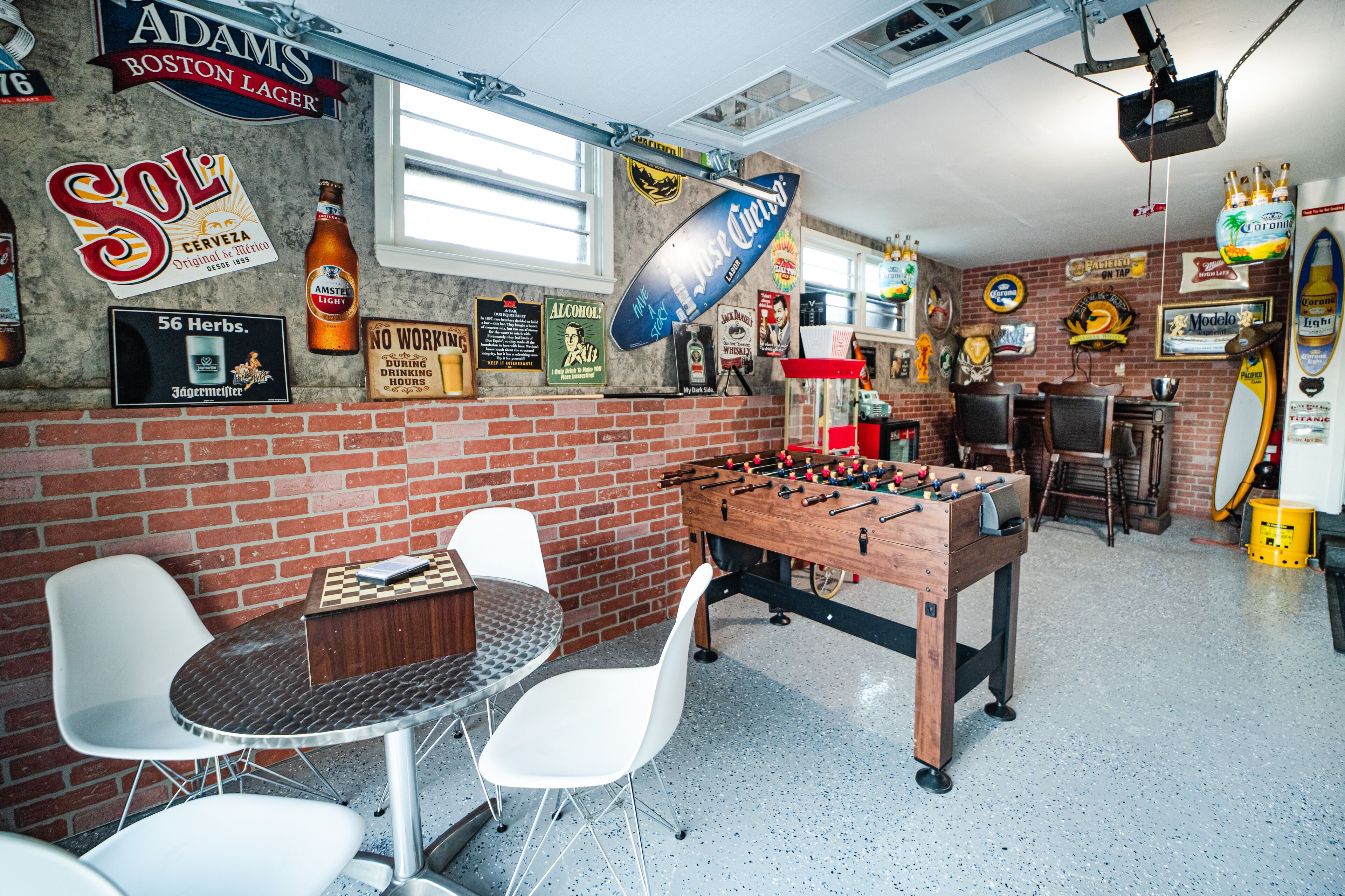 A room with a foosball table, a brick wall, and various posters and signs.