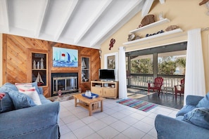 Ein Wohnzimmer mit Kamin, Fernseher und einem Balkon mit roten Stühlen.