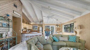 A cozy living room with a large sectional sofa, a glass coffee table, and a kitchen in the background. - Doubloon: Beach, Private Pool and Boating....This 4 Bedroom home has it all!! (Placida)