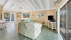 A spacious living area with a large sofa, a dining table, and a TV on a stand. - Doubloon: Beach, Private Pool and Boating....This 4 Bedroom home has it all!! (Placida)