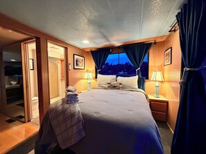 Een hotelkamer met een bed, twee bedlampen, een raam met gordijnen, een deur en een aan de muur hangend schilderij.