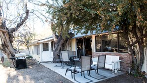 A patio with outdoor seating, a barbecue grill, and a building with large windows. - Historic Date Creek Ranch (Congress)