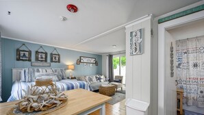 A bedroom with a bed, bedside table, and a view of the outdoors. - Charming Dennis Port Getaway for Two with Pool & Walk to Beach (Dennis Port)