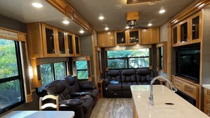 Ein modernes Wohnmobil-Interieur mit Küchenbereich, Sitzgelegenheiten und einem großen Fenster.