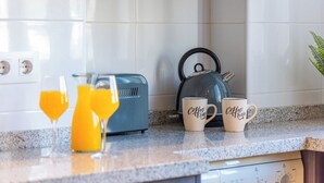 Una encimera de cocina con un tostador, dos tazas de café y dos vasos de jugo de naranja.