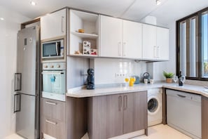 A modern kitchen with built-in appliances, a washing machine, and a coffee maker.