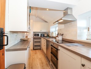 Eine moderne Küche mit weißen Schränken, einer Holz Arbeitsplatte, einem Einbauofen und einer Mikrowelle.