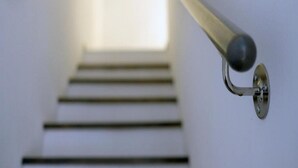 A metal handrail with a round knob, attached to a wall with a metal plate. - Apartments Blue Lavender (Cres)