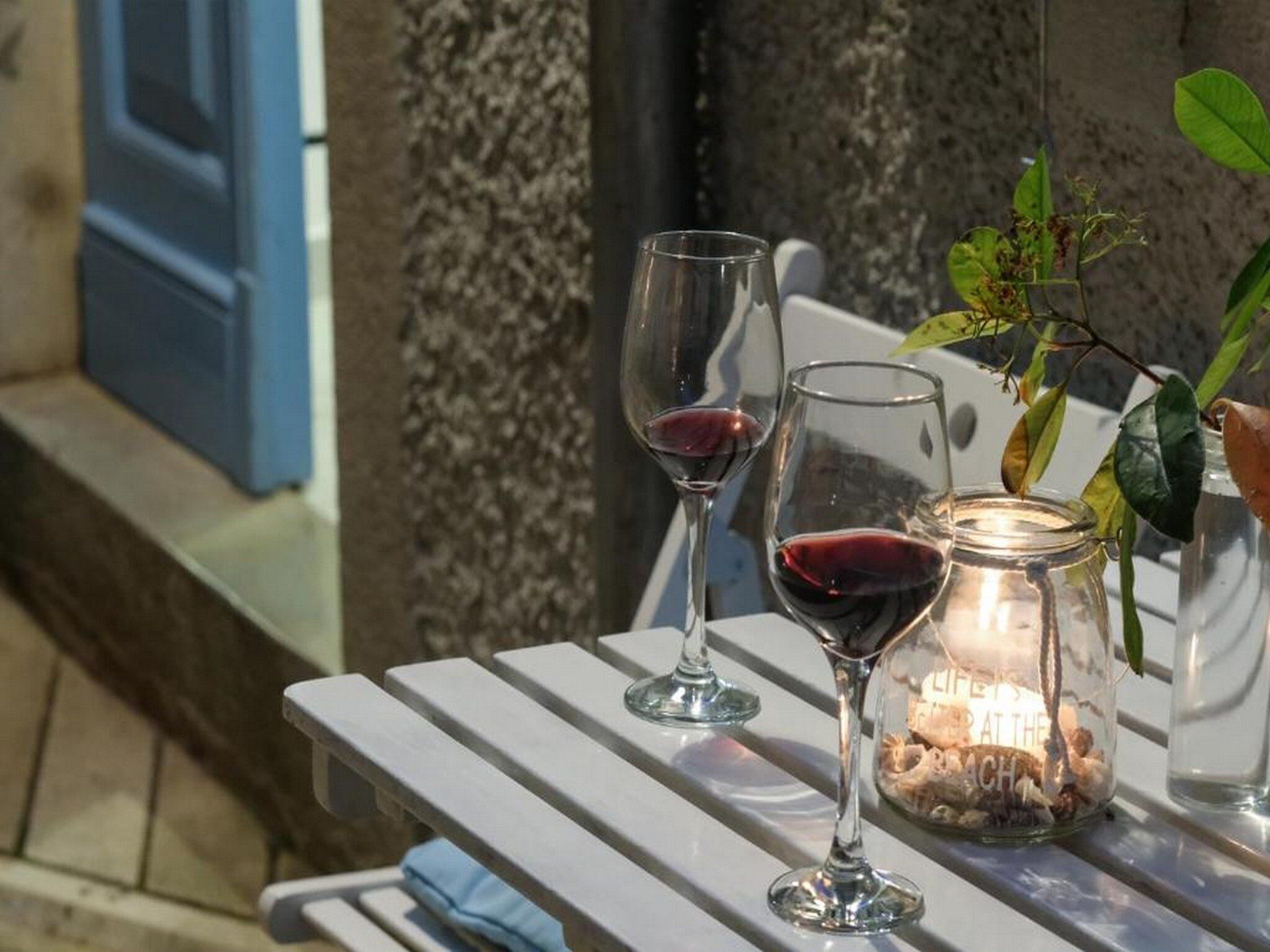A table with two wine glasses and a candle jar.