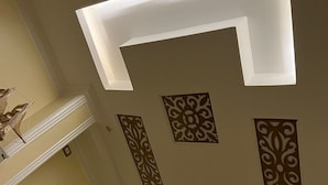 Teto com iluminação embutida e painéis decorativos.