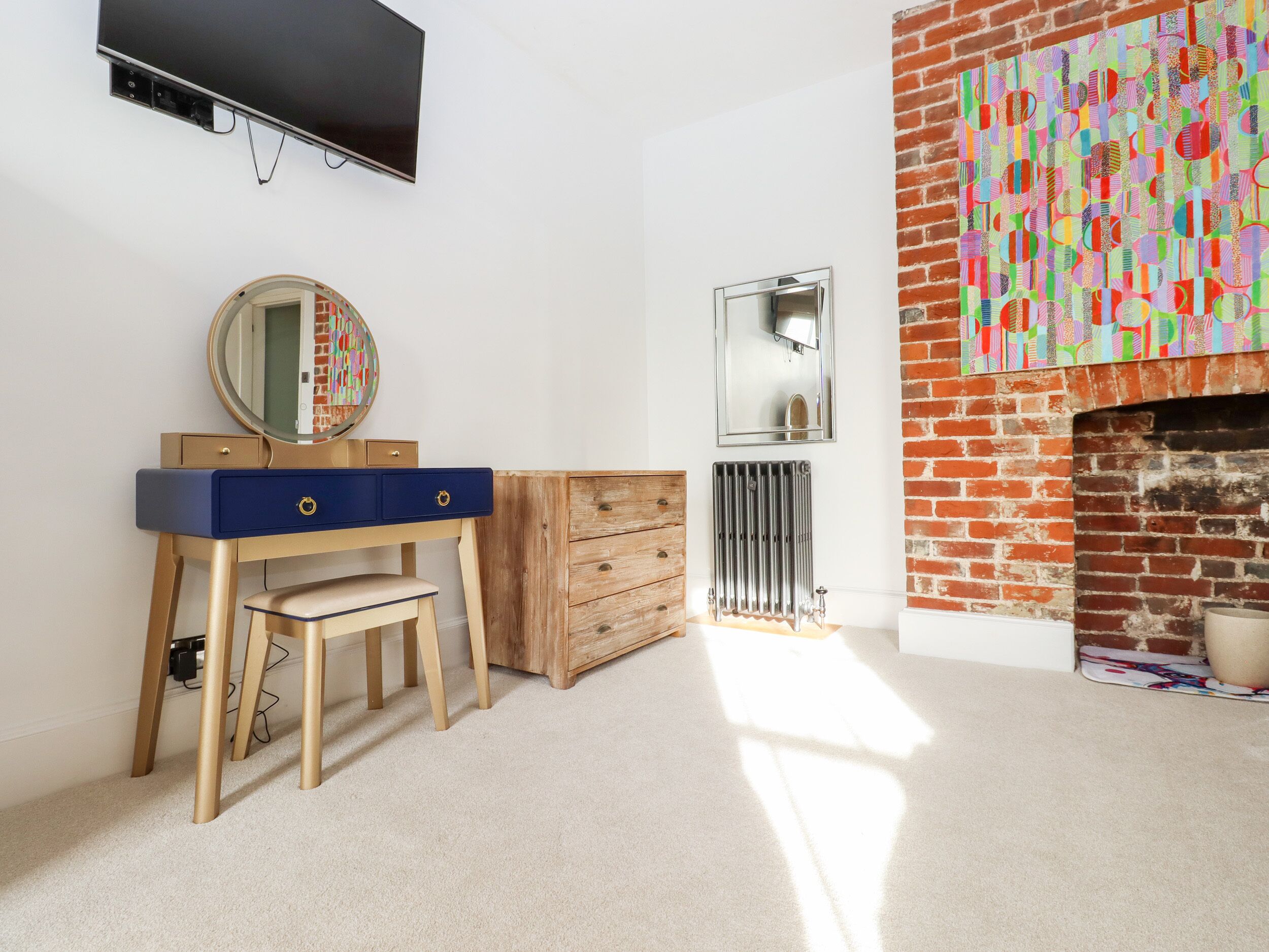 Ein Zimmer mit einem Holznähefrack, einem Spiegel, einer Heizung und einer Ziegelwand.