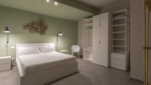 A bedroom with a large bed, a wardrobe, and a chair. - San Luca Apartments - Grillo by Wonderful Italy (Genoa)