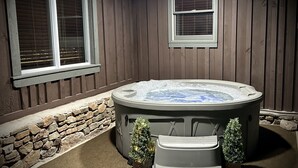 A hot tub in a covered outdoor area with wooden walls and stone accents.