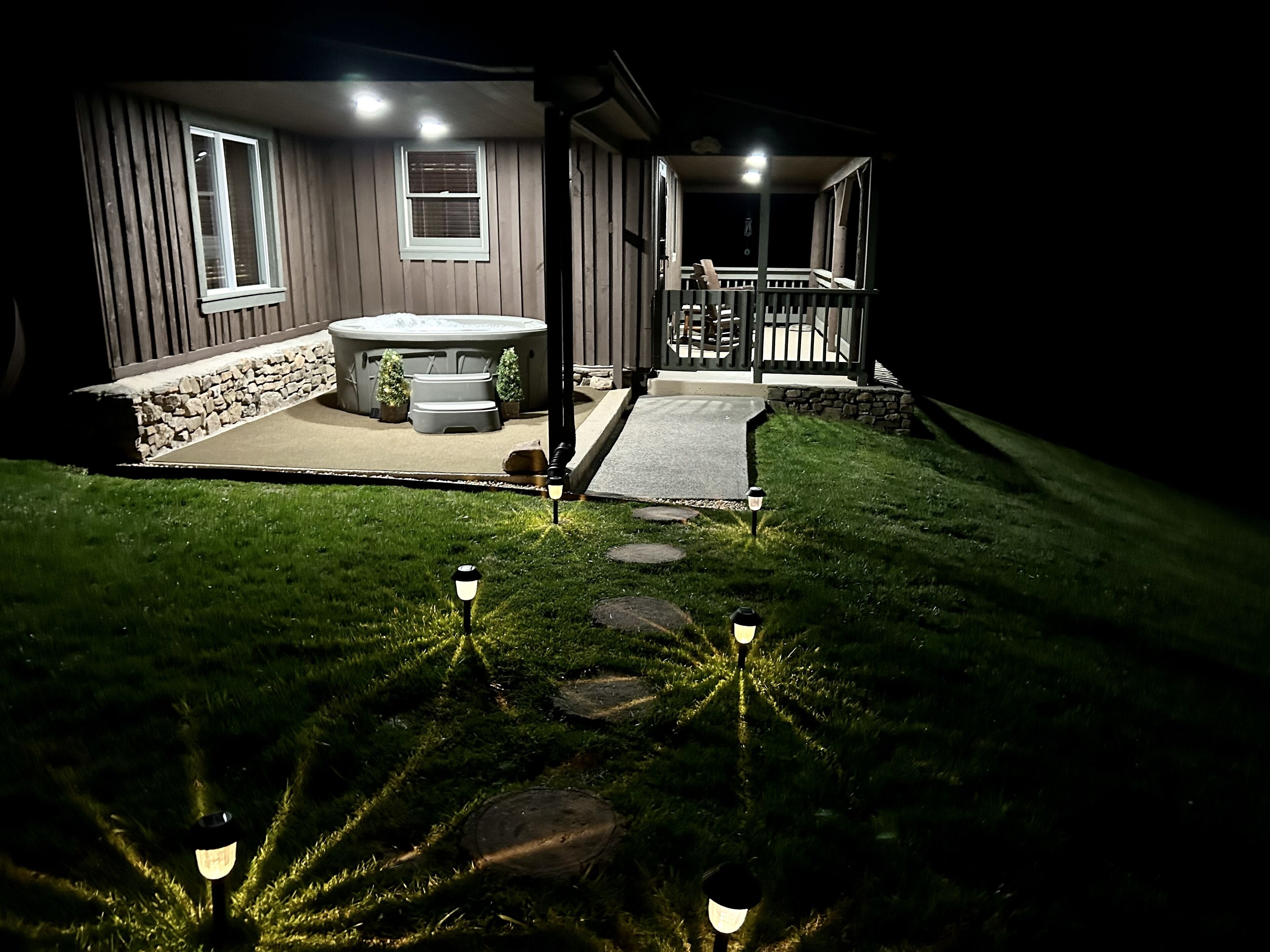 Una casa con jacuzzi, un patio de piedra y una terraza de madera.