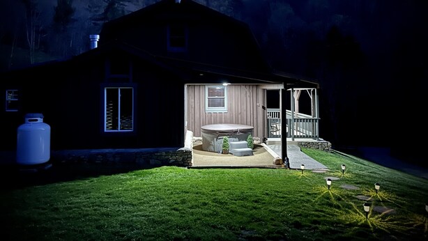 A house with a covered patio, a large water heater, and a grassy yard.