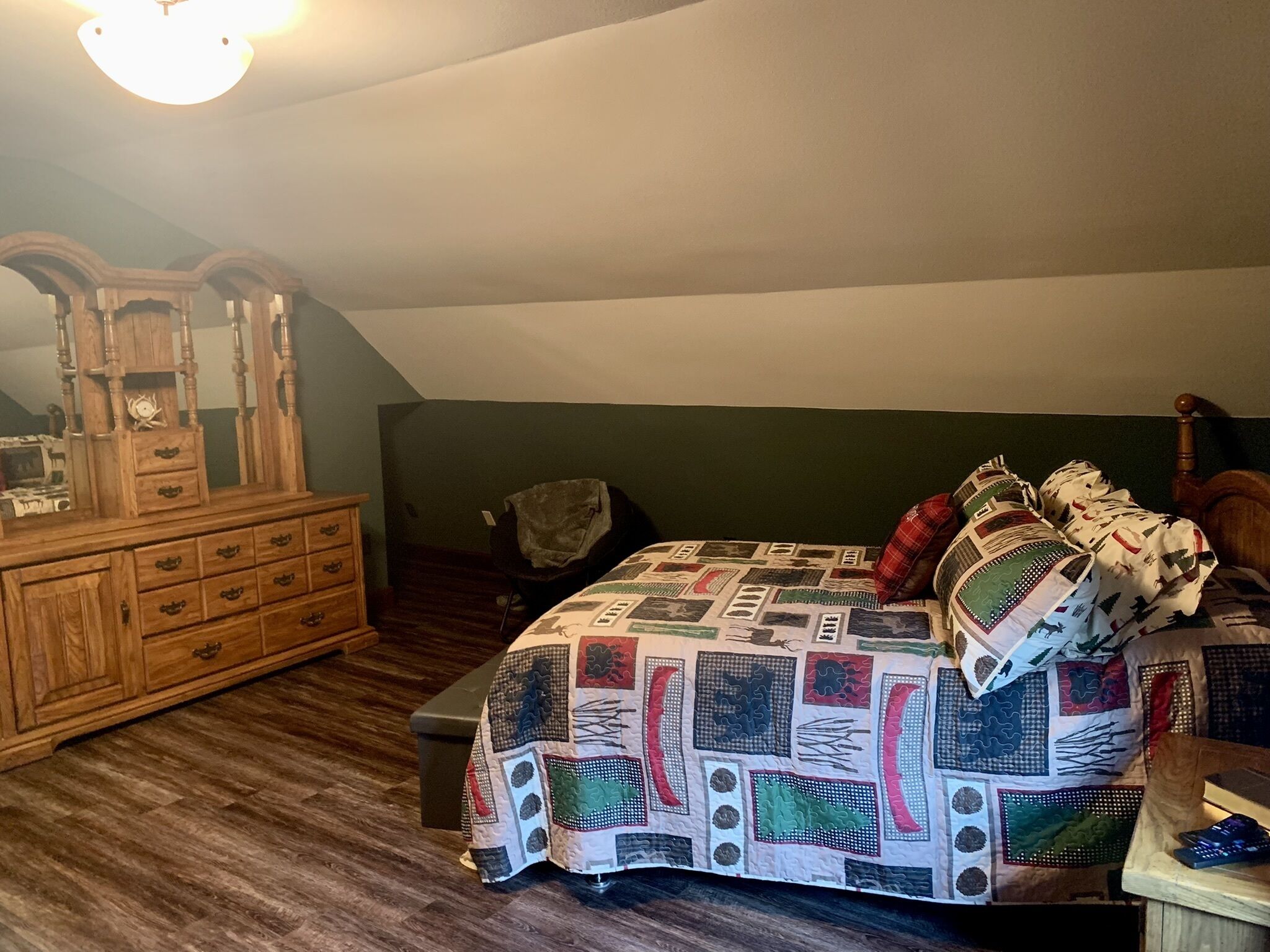 Ein Schlafzimmer mit einem hölzernen Schminktisch, einer gesteppten Bettdecke, einem Stuhl und einem Holz-Kopfteil.