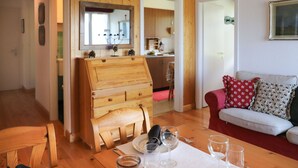 A dining area with a wooden table set for four, a red sofa, and a kitchen in the background. - Nice apartment for 4 people with WIFI, TV, balcony and panoramic view (Bluche)