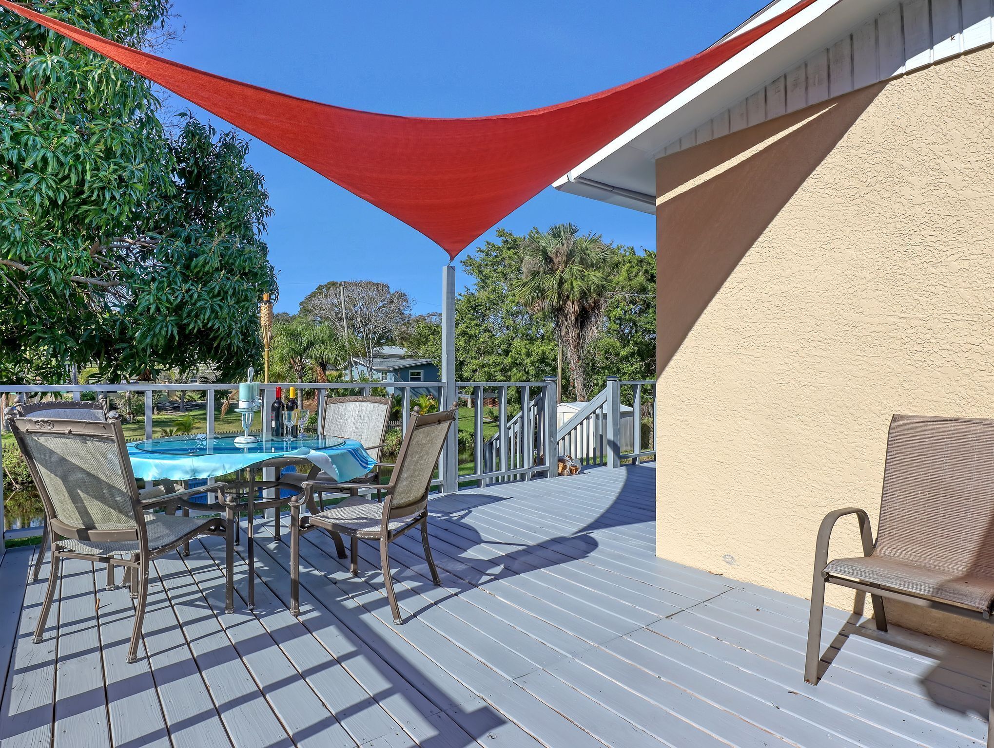 Terraza techada al aire libre con mesa de billar, sillas y una vela de sombra roja.