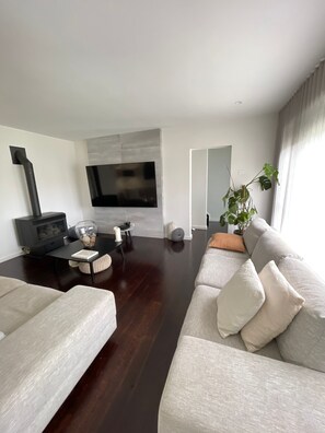 A modern living room with a fireplace, a flat-screen TV, and a large sofa. - Beautiful Home Laverton (Laverton)