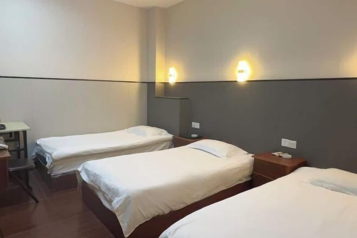 A hotel room with two single beds, a desk, and a chair.
