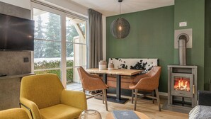 Uma sala de estar acolhedora com lareira, televisão e área de jantar com cadeiras e mesa.