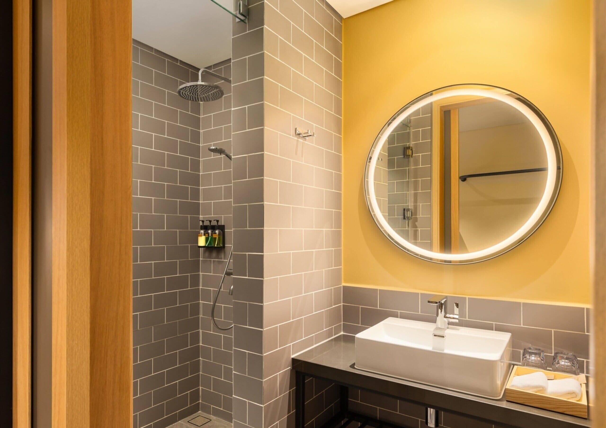 A modern bathroom with a shower, a sink, and a mirror.