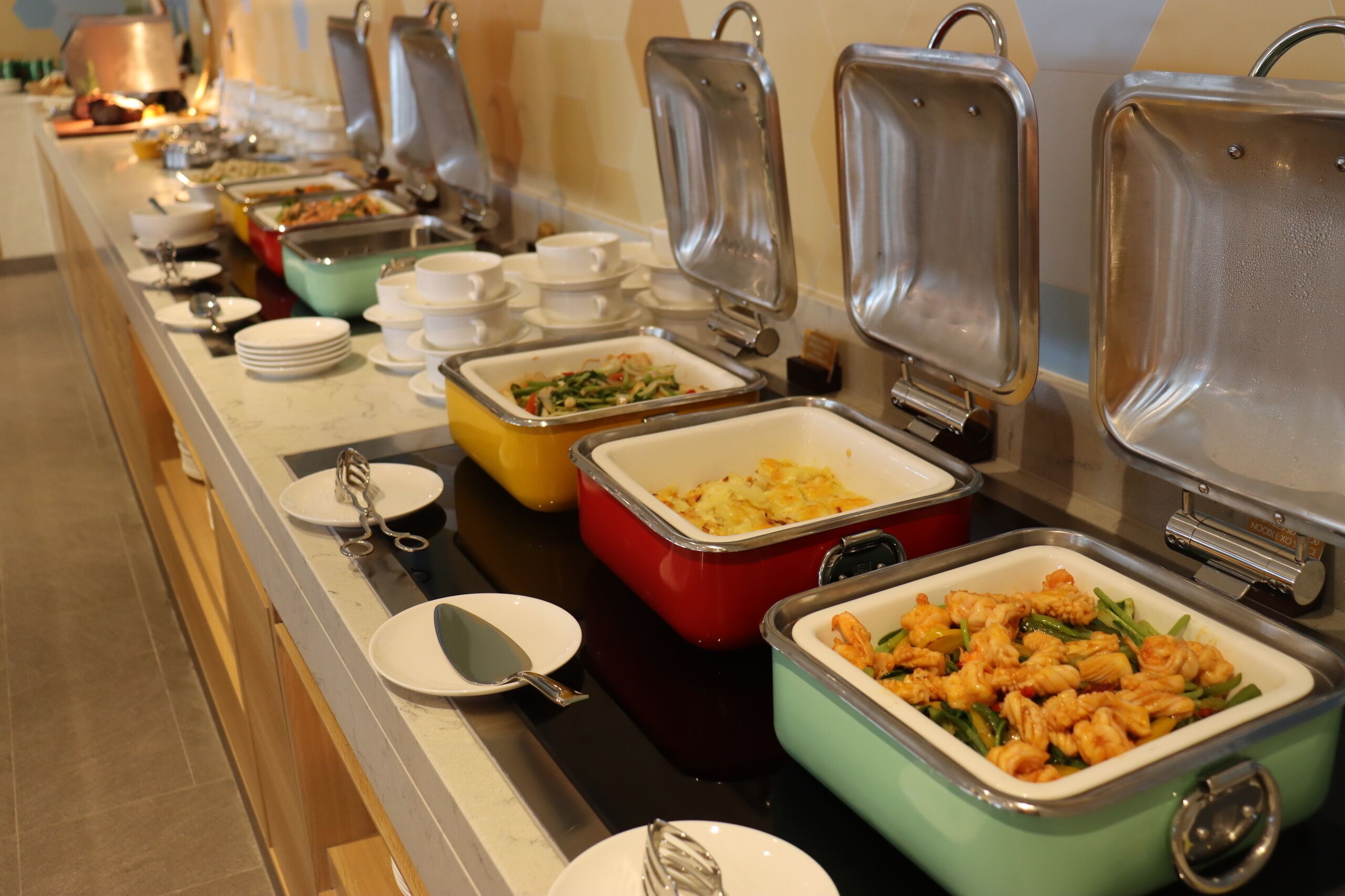En buffet med forskellige madbeholdere og serveringsbestik.