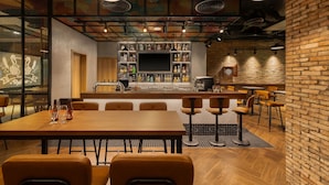 A modern bar area with a long wooden table, bar stools, and a variety of bottles. - HIIVE by fusion Binh Duong - VSIP 1 (Ho Chi Minh City)