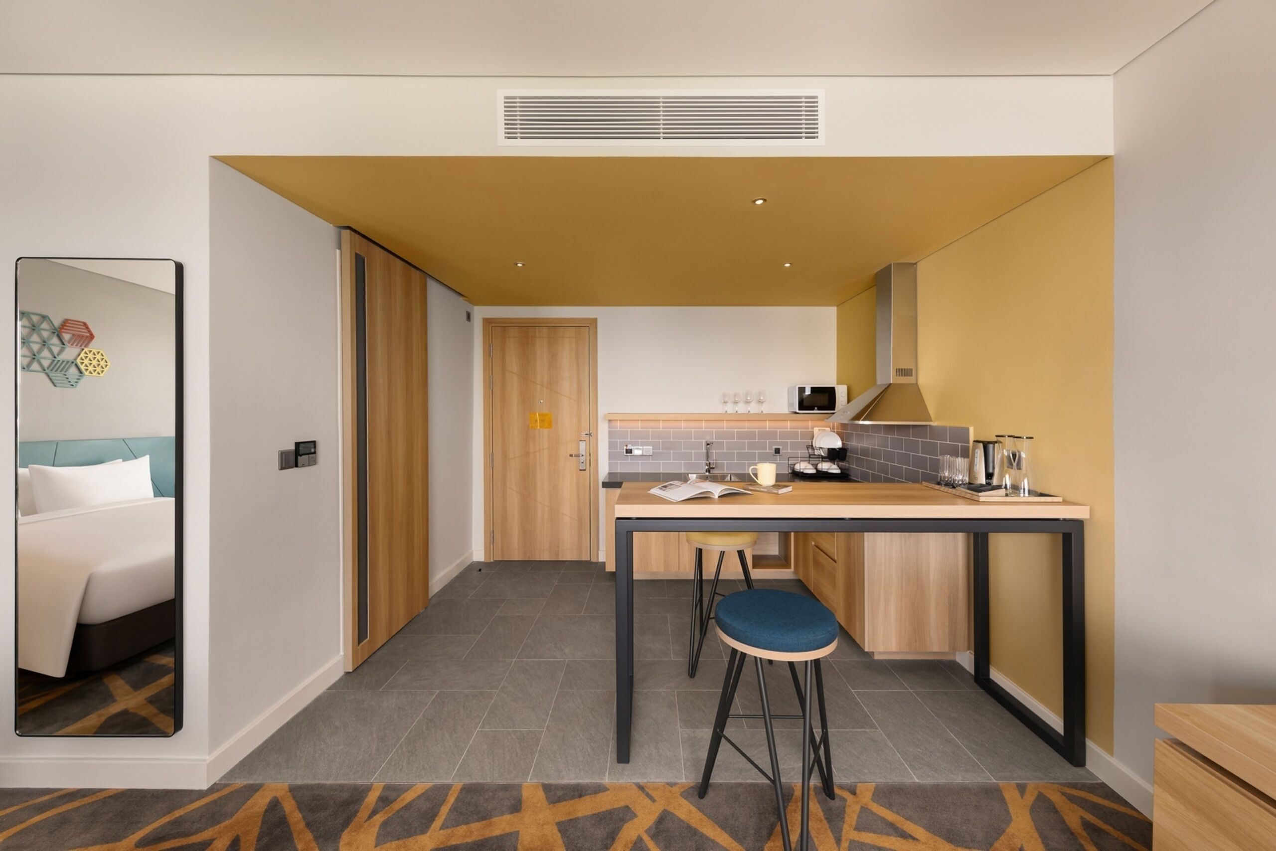 Habitación de hotel pequeña con cama, kitchenette y baño.
