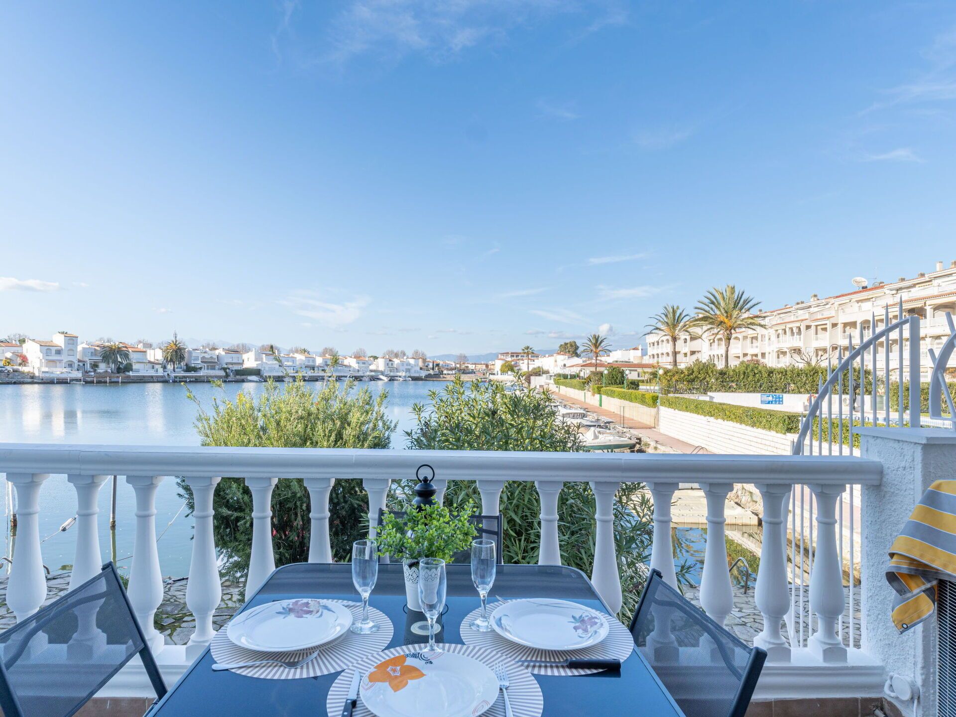 Mesa de jantar posta numa varanda com vista para uma marina e edifícios.