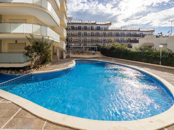 Une piscine entourée d’un immeuble à plusieurs étages doté de balcons.