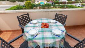 A round table set for four with a checkered tablecloth, plates, cutlery, and a bowl of fruit. - Cosy apartment for 4 people with WIFI, pool, TV and terrace (Salou)