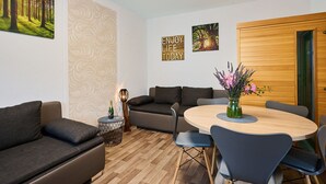 A modern living room with a round wooden table, grey sofas, and a wooden door. - Lovely apartment for 6 guests with WIFI, TV and balcony (Jilemnice)