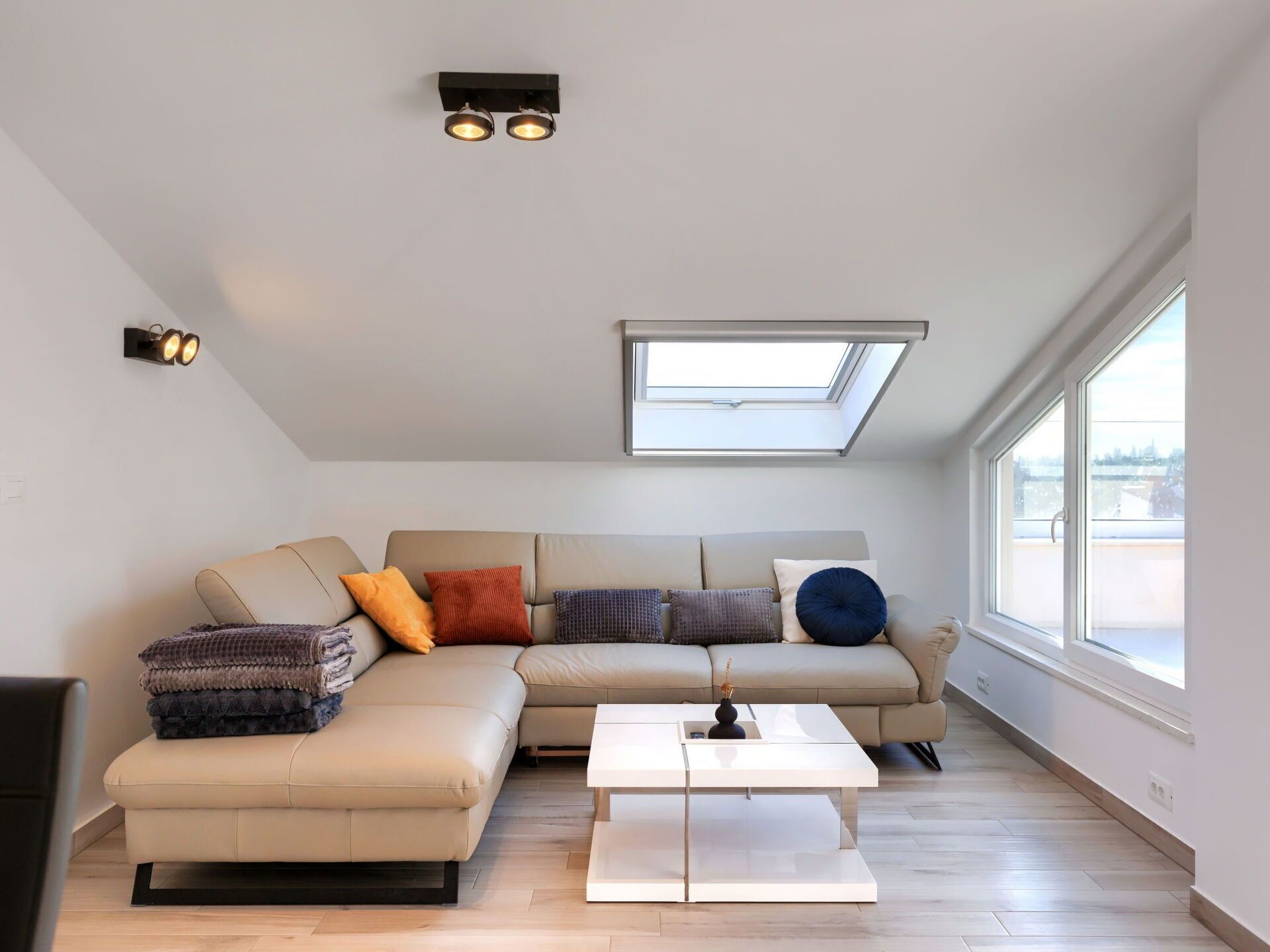 Een moderne woonkamer met een hoekbank, een salontafel en een dakraam.