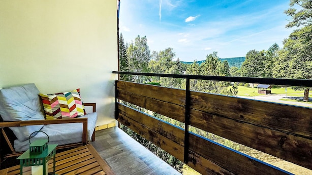 A balcony with a wooden bench, a small table, and a green lantern. - Nice apartment for 4 guests with WIFI, TV, balcony and pets allowed (Jilemnice)