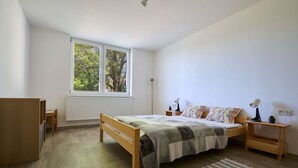 A bedroom with a wooden bed, a nightstand, a desk, and a window with blinds. - Nice apartment for 4 guests with WIFI, TV, balcony and pets allowed (Jilemnice)