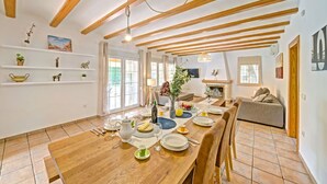 Un comedor con una mesa de madera dispuesta para una comida, un sofá al fondo y una chimenea.