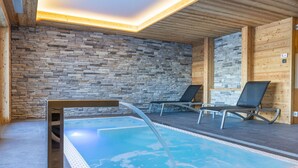 A swimming pool with two lounge chairs, a stone wall, and wooden paneling. - Cosy apartment for 6 guests with hot tub, WIFI, TV and balcony (Basse-nendaz)
