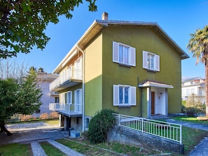 A two-story house with a balcony, a stone pathway, and a small garden. - Beautiful apartment in villa for 16 people with WIFI, TV, balcony and pets allowed (Dervio)
