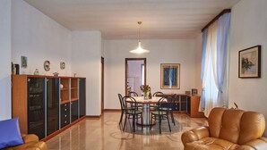 Ein geräumiges Wohnzimmer mit einer Ledersofa, einem Essbereich mit einem runden Tisch und einer Vitrine mit Glastüren.
