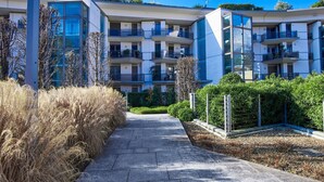 A modern apartment building with multiple balconies, a paved walkway, and surrounding greenery. - Beautiful apartment for 6 people with WIFI, TV and patio (Lecco)
