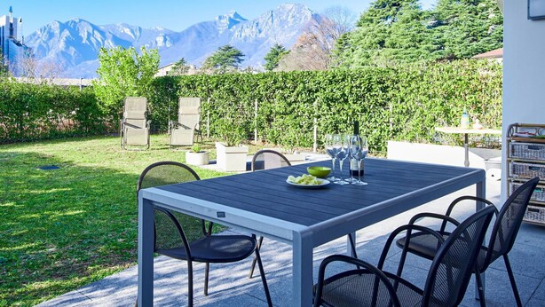 A patio with a table set for dining, chairs, and a view of mountains. - Beautiful apartment for 6 people with WIFI, TV and patio (Lecco)