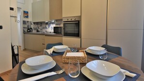 A modern kitchen with a dining table set for four, including plates, bowls, glasses, and cutlery.