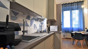 A modern kitchen with a gas stove, sink, and a microwave. There is a dining area with a table and chairs.